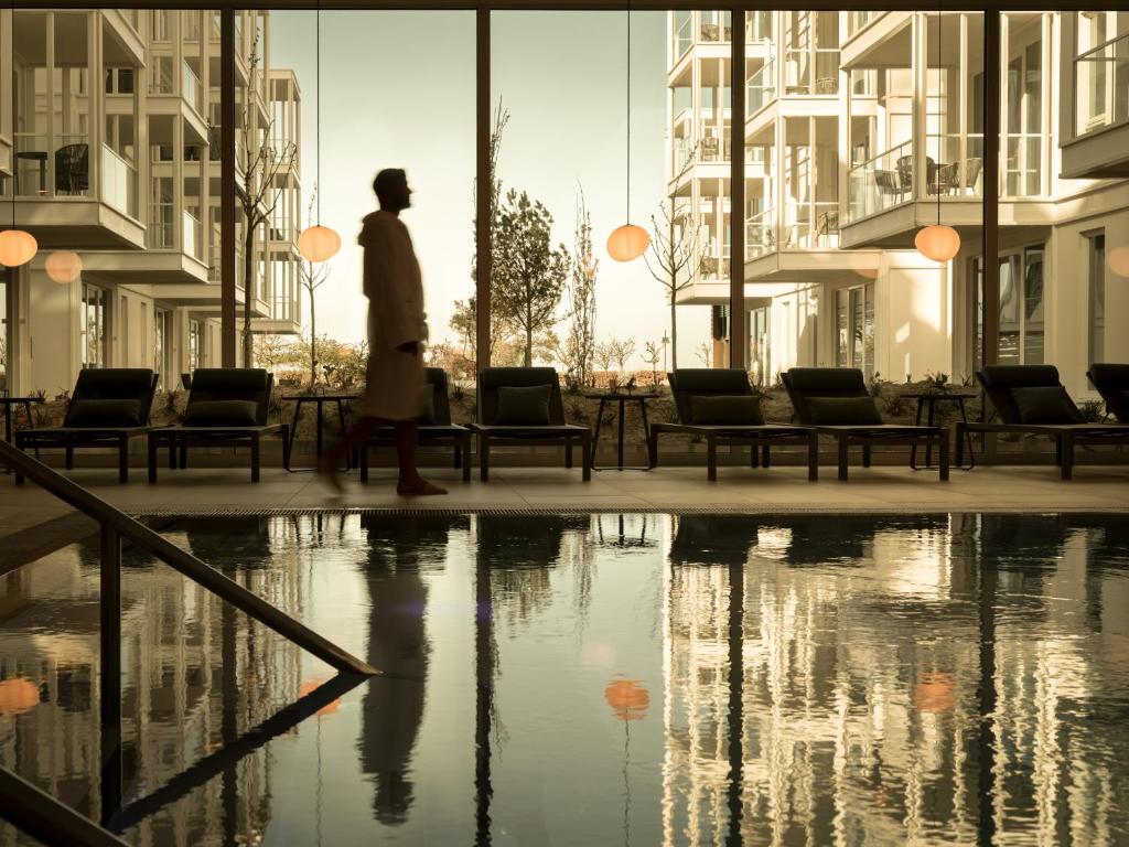 une personne se promenant au-delà d'une piscine d'eau dans un bâtiment dans l'établissement the breeze, à Ahlbeck