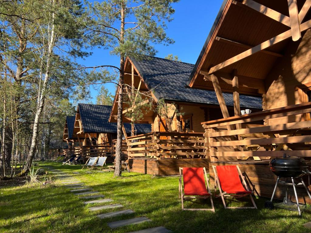 a log cabin with two chairs and a grill at BORSKÓWKA domki z balią z jacuzzi in Borsk