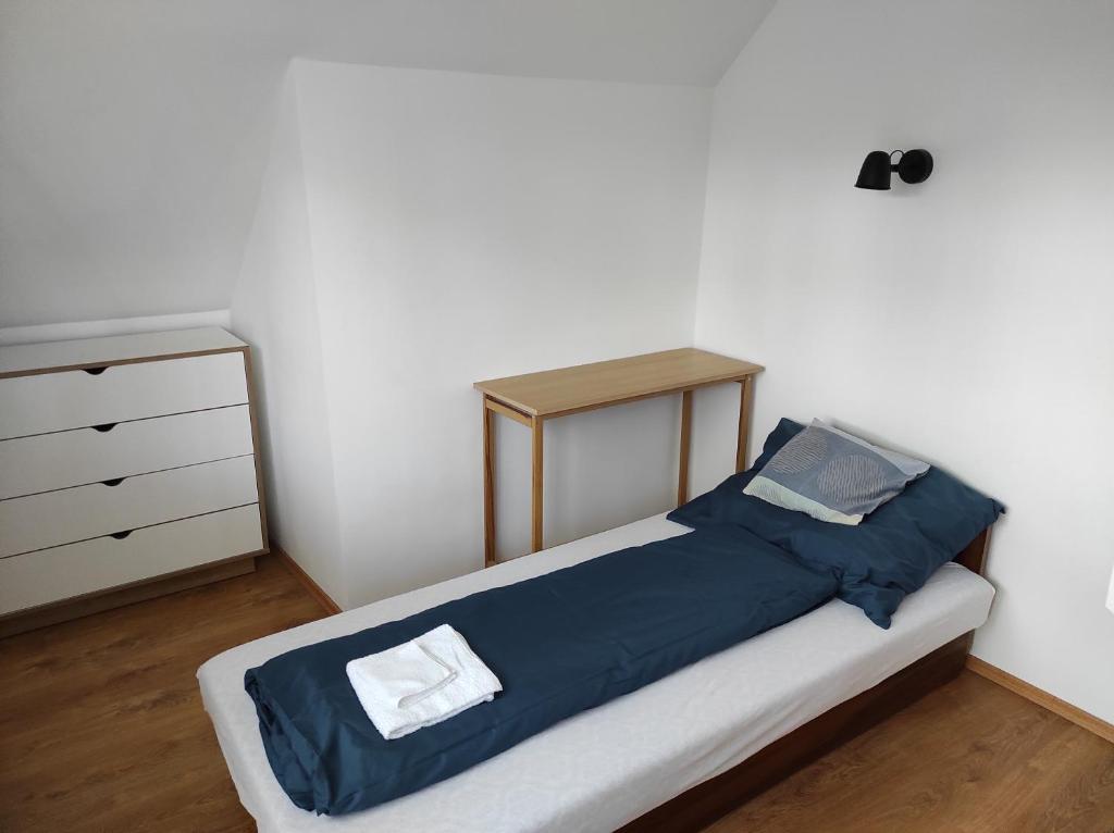 ein Bett mit einer blauen Decke und einer Kommode in einem Zimmer in der Unterkunft Apartman Garami Porta in Mezőkövesd