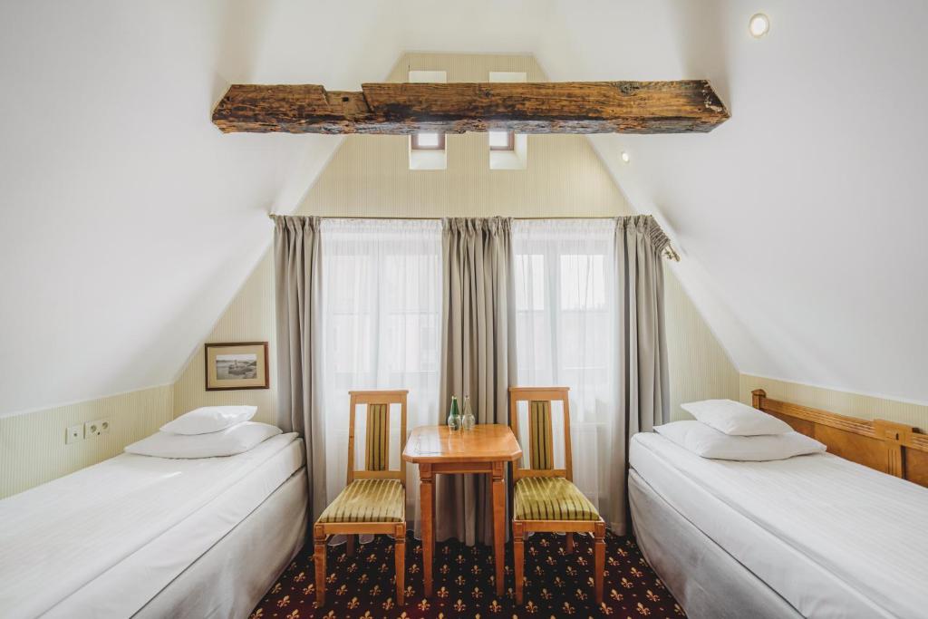 duas camas num quarto com uma mesa e uma janela em Solaris em Toruń