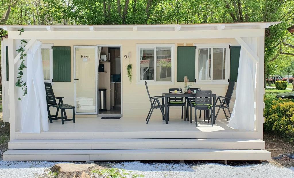 een afgeschermde veranda met een tafel en stoelen bij Luxe Mobilehome with dishwasher and airconditioning included fits 4 adults and 1 child, Ameglia, Ligurie, Cinqueterre, North Italy, Beach, Pool, Glamping in Ameglia