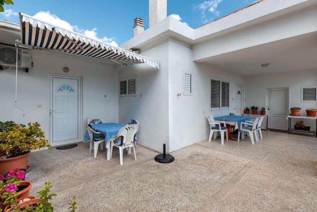 eine Terrasse mit einem blauen Tisch und Stühlen sowie ein Haus in der Unterkunft Sole Solei apartman 2 - Meljine in Meljine