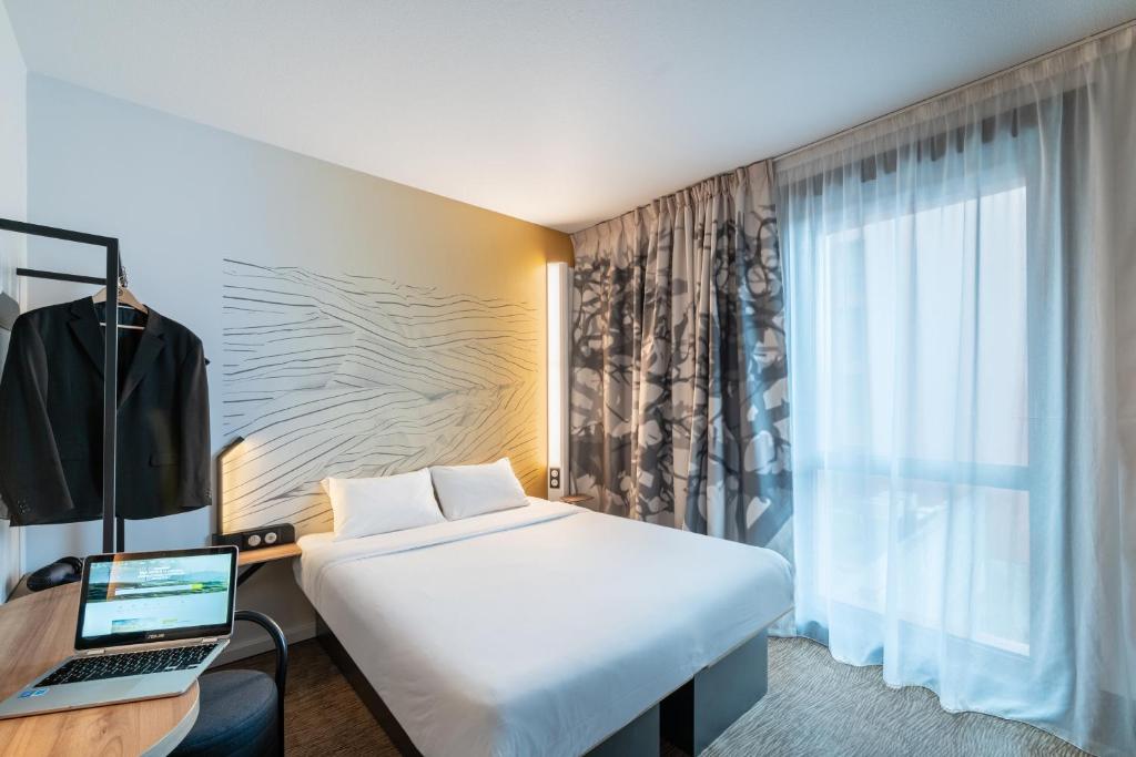 une chambre d'hôtel avec un lit et un ordinateur portable sur un bureau dans l'établissement B&B HOTEL Saintes, à Saintes
