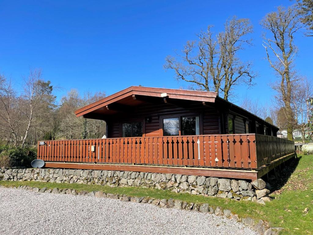 a small log cabin with a stone wall at Beautiful Norwegian Lodge in Kippford with Garden Pass the Keys in Dalbeattie
