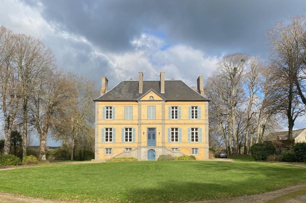uma grande casa amarela com três chaminés num campo de relva em Le Château des Portes 
