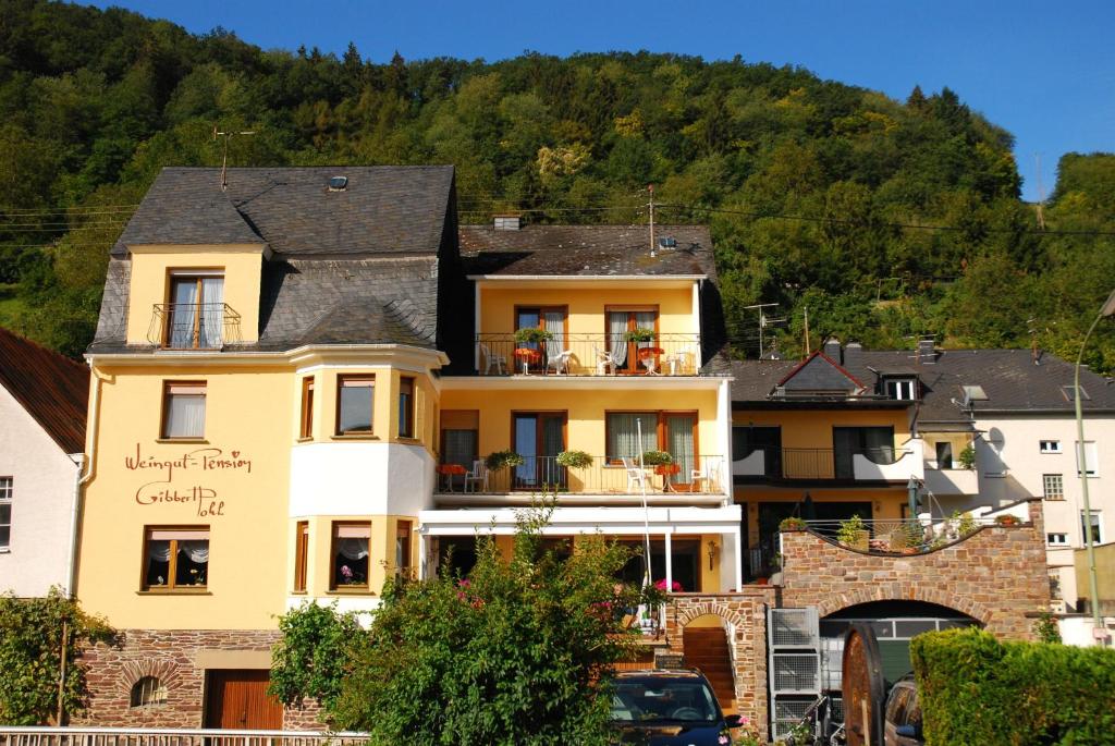 un gran edificio amarillo frente a una montaña en Weingut Pension Gibbert-Pohl, en Briedel