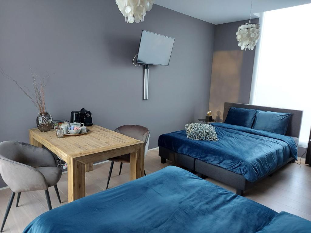a bedroom with two beds and a wooden table and a table sidx sidx at Bed & Wellness Boxtel, 4 persoonskamer met eigen badkamer in Boxtel