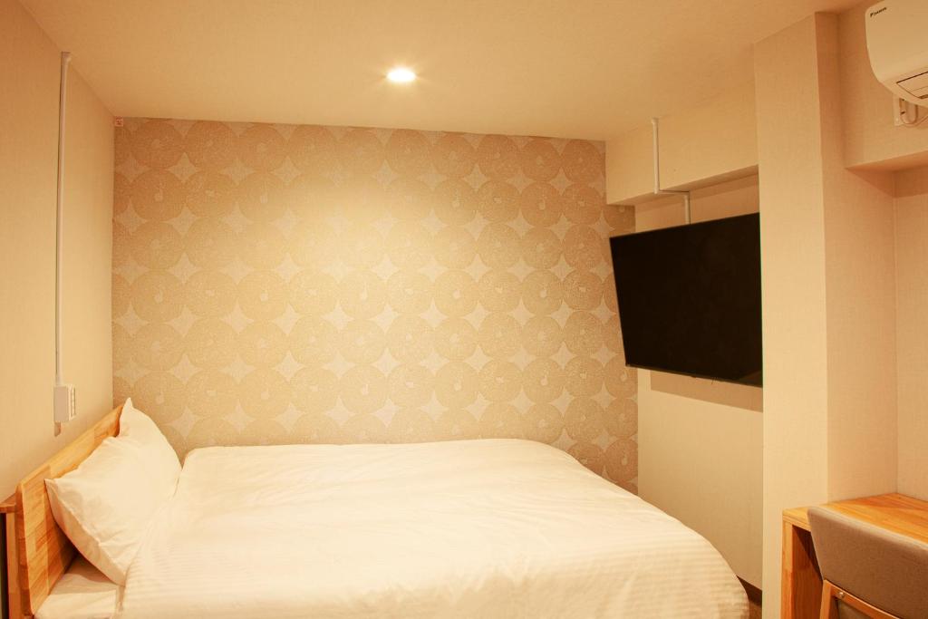 a bedroom with a white bed and a flat screen tv at Sauna & Cabin Thermae-yu Nishiazabu in Tokyo