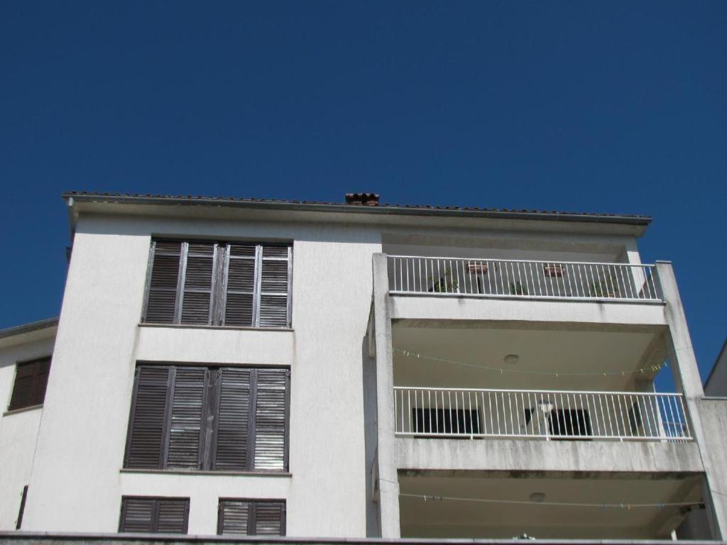 a white building with two balconies and a blue sky at Apartments Lory in Rabac
