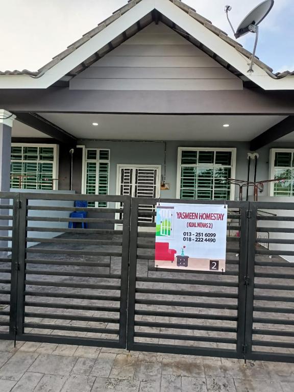 a house with a sign in front of a fence at Yasmeen Homestay Kijal Nenas 2 in Kijal