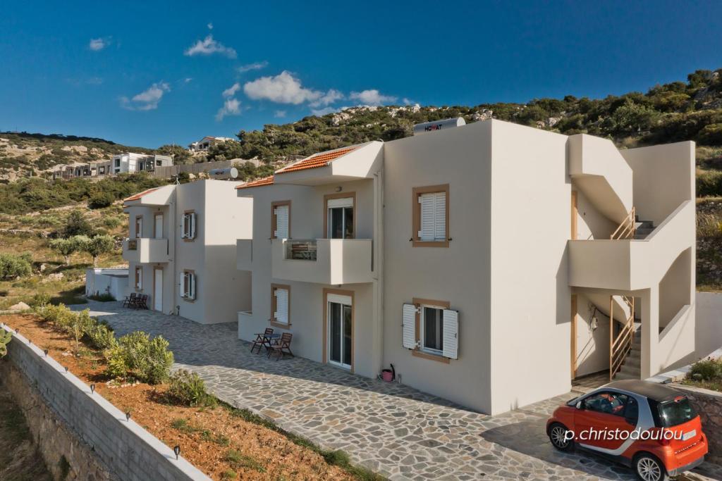 a row of white houses with a red car parked in front at Karpathos City View Apartments in Karpathos