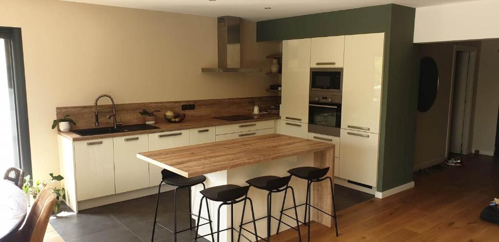 a kitchen with a wooden counter and stools in it at Villa T4 avec piscine in Lucciana
