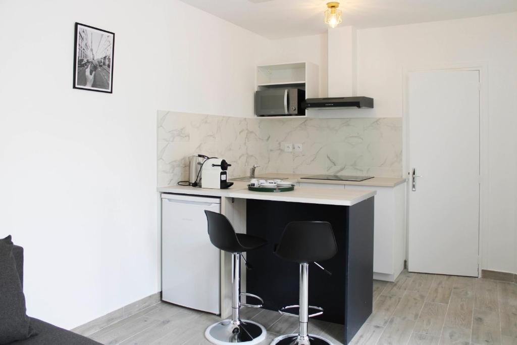 una pequeña cocina con encimera y 2 taburetes en Beautiful apartment of 20 m with terrace, en Ivry-sur-Seine