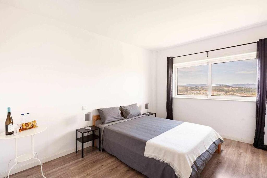 a white bedroom with a bed and a large window at Bossa Nova GuestHouse in Braga