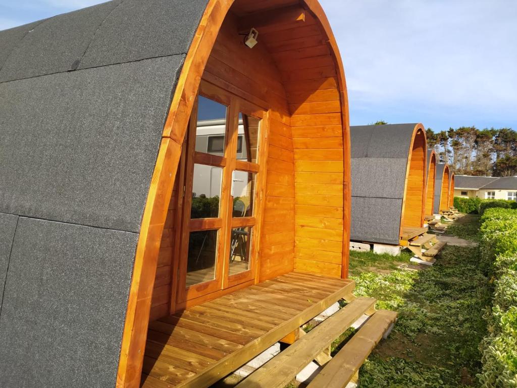 een houten hut met een raam op een dak bij Bungalow 4 personas - Camping Playa de Tapia in Tapia de Casariego