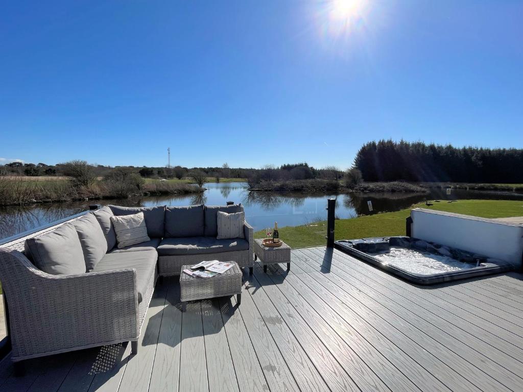 a patio with a couch and a fire place at Beautiful Luxury Lakeside Lodge Hot Tub Views Pass the Keys in Annan