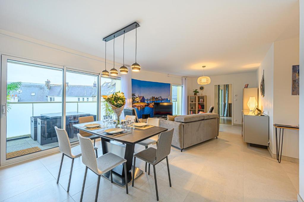 a dining room and living room with a table and chairs at L'Audacieux - Appt neuf avec vue sur les toits in Vannes