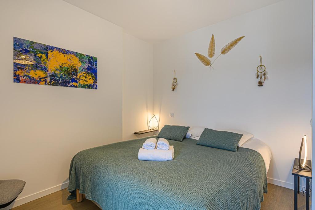 una camera da letto con un letto con due asciugamani sopra di L'Audacieux - Appt neuf avec vue sur les toits a Vannes