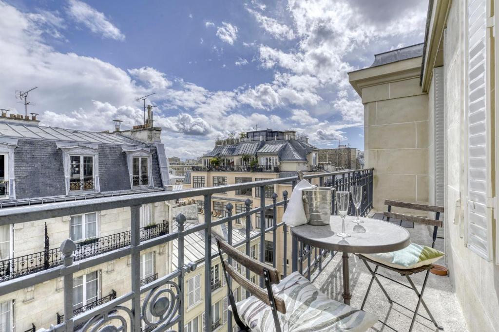 un balcon avec une table et des chaises sur un immeuble dans l'établissement Le Petit Parisien - Au Cœur de Montparnasse, à Paris