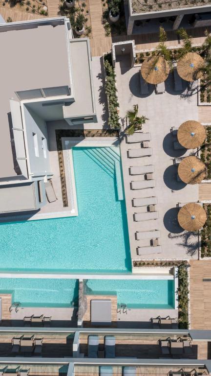 einen Blick über einen Pool mit Sonnenschirmen in der Unterkunft Sun City Luxury Apartments in Asgourou