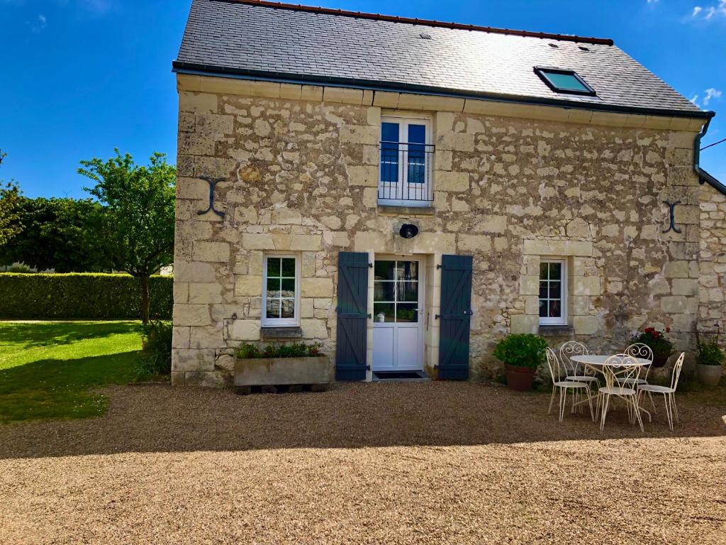 una casa de piedra con una mesa y sillas delante de ella en La Grange de l'Olive, en Chinon