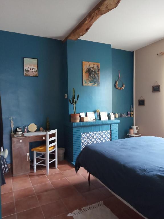 - une chambre avec des murs bleus, un lit et un bureau dans l'établissement La Vicoise Accueillante, à Vic-Fezensac