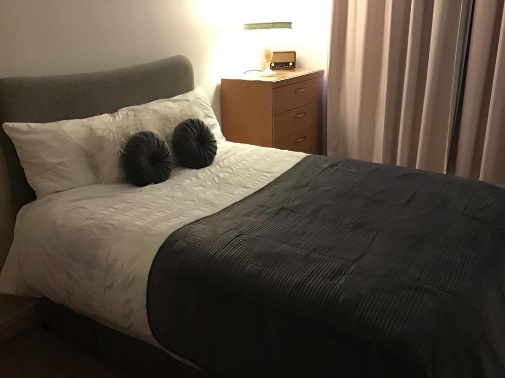 a bedroom with a bed with two black mitts on it at Dovedale Apartment in Moreton