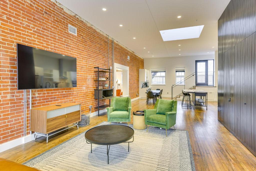a living room with a brick wall and a tv at Downtown Omaha Getaway with Deck and Gas Grill! in Omaha