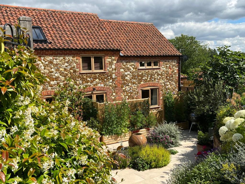 a stone house with a garden in front of it at The Norfolk Haybarn in Sedgeford