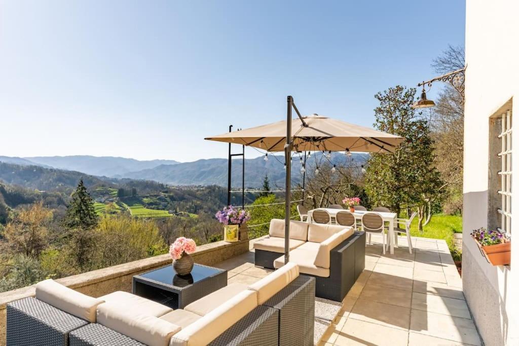 a patio with white couches and an umbrella at * Farmhouse with views * Walk to everything in Barga