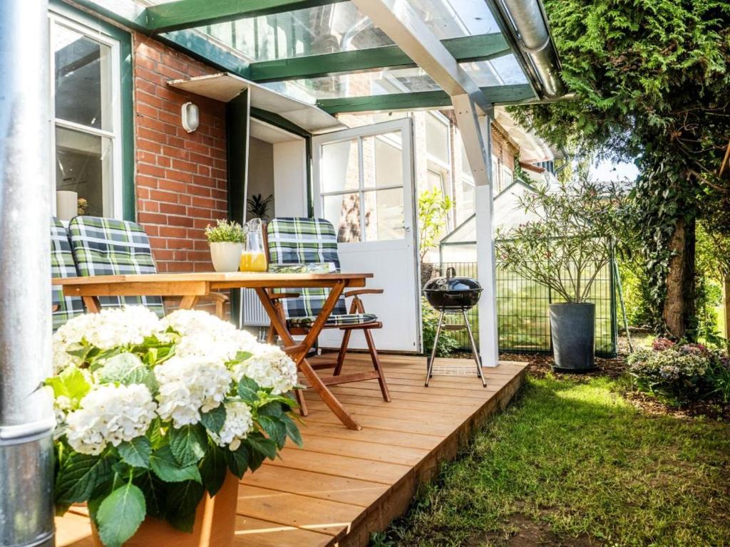 a patio with a wooden table and some white flowers at Ferienwohnung Meer und Muh in Strenglin