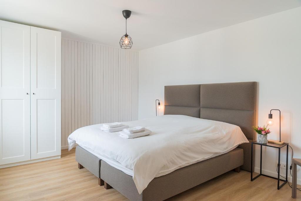 um quarto com uma cama grande e lençóis brancos em MAISON ROBERT em Modave