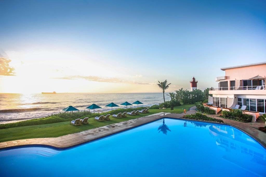 una piscina di fronte a una casa e all'oceano di Beverly Hills a Durban