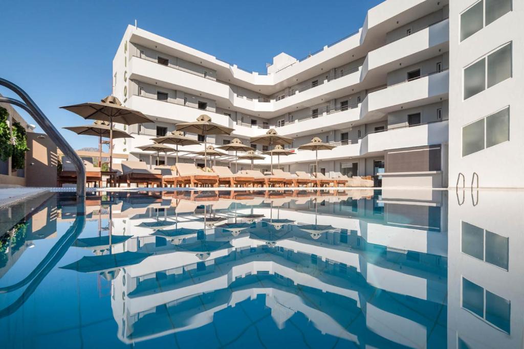 カルダメナにあるNicolas Grand Suites, Adults Onlyのプールとパラソル付きのホテルの外の景色を望めます。