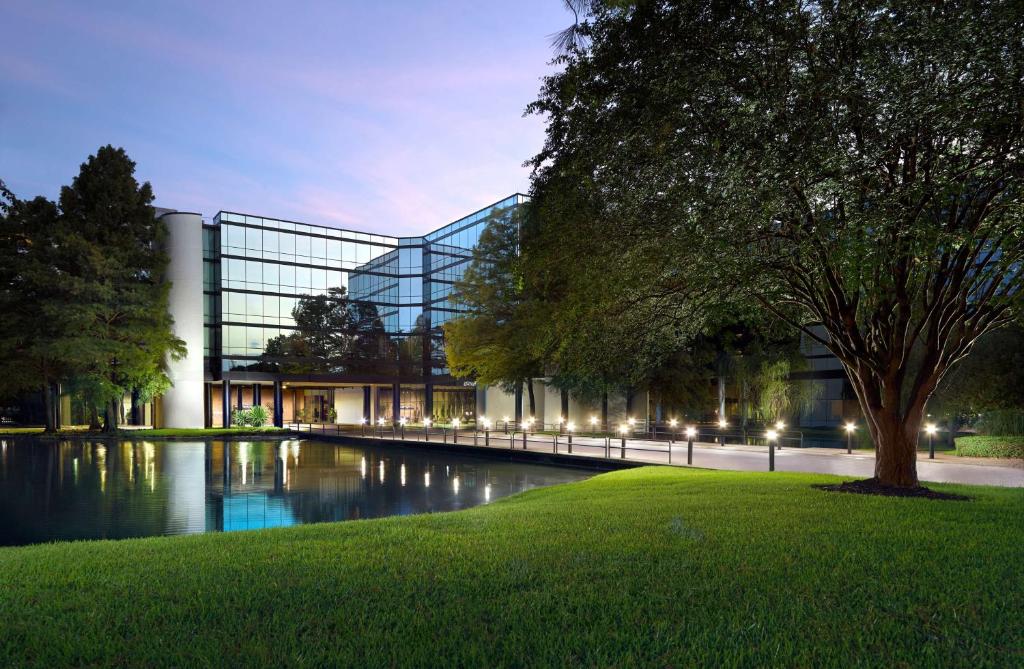 a large glass building with a pond in front of it at Hyatt Regency Houston West in Houston