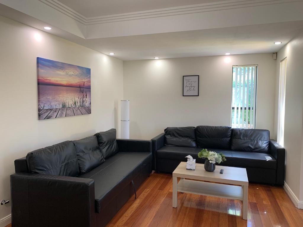 a living room with a black couch and a table at Comfy place with all in Revesby