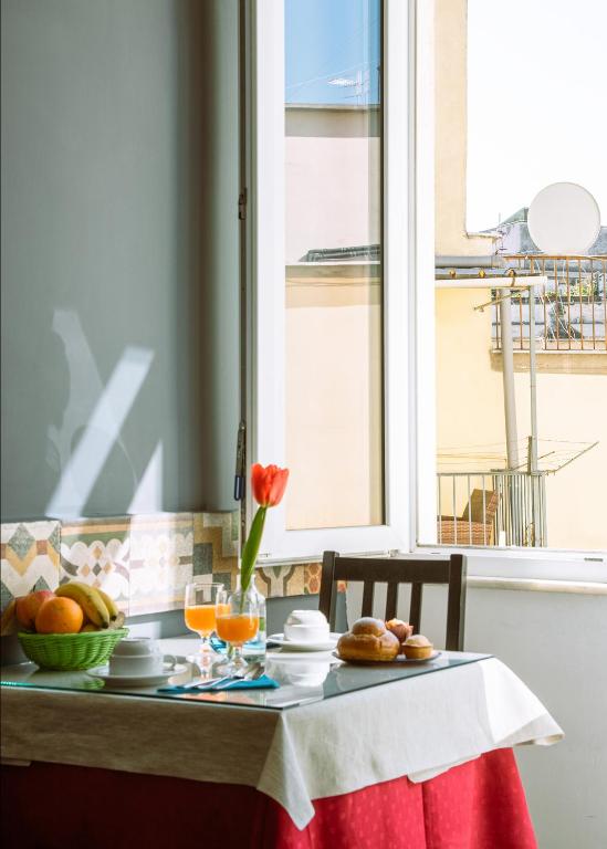 Una mesa con un bol de fruta y una ventana. en Carafa Suite B&B, en Nápoles