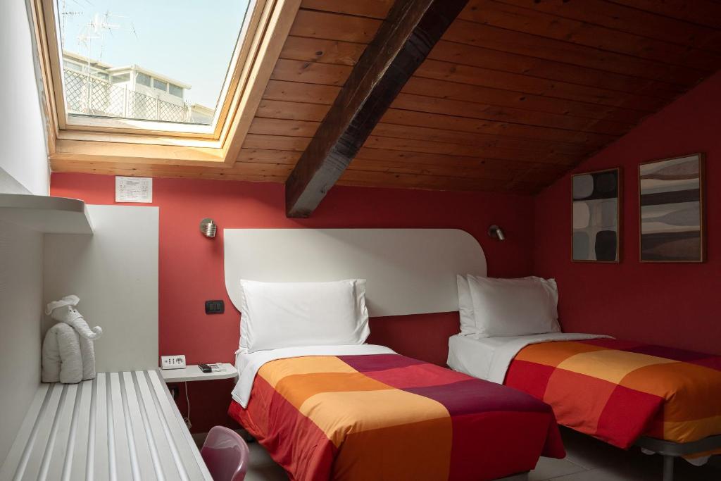 Duas camas num quarto com paredes vermelhas e uma janela em Carafa Suite By Enjoy Napoli em Nápoles