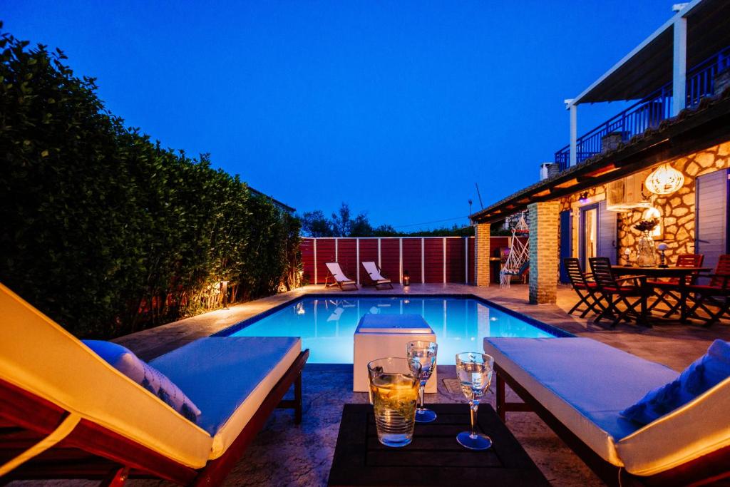 a swimming pool with two chairs and glasses of wine at Villa Rosemarie - Luxurious Villa with Pool Just Steps Away from the Sea By Villa Mana Gers in Psarou