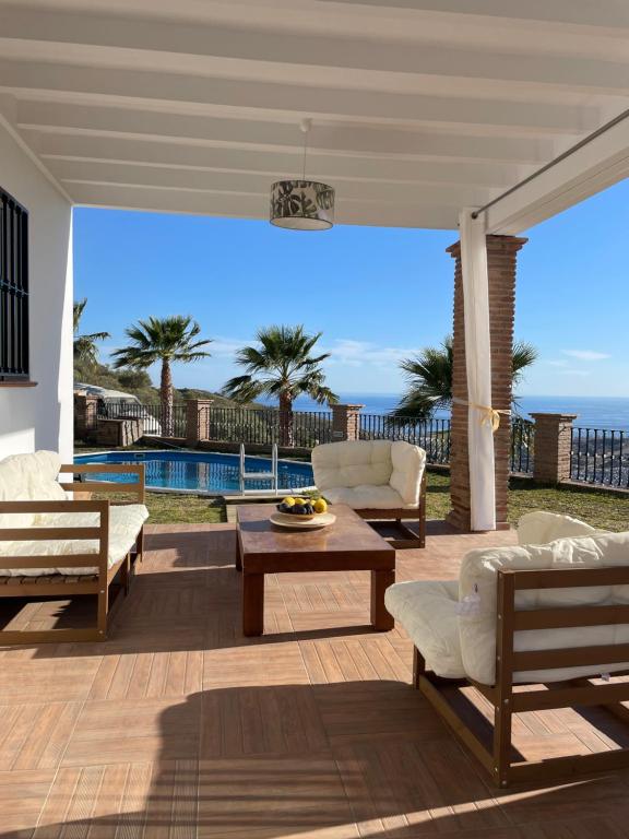 a patio with chairs and a table and a pool at Casa Helen in Torrox