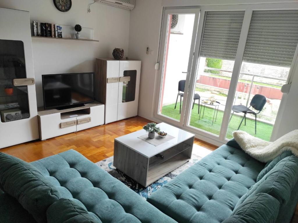 een woonkamer met een blauwe bank en een televisie bij Apartman Dionis Centar in Trebinje