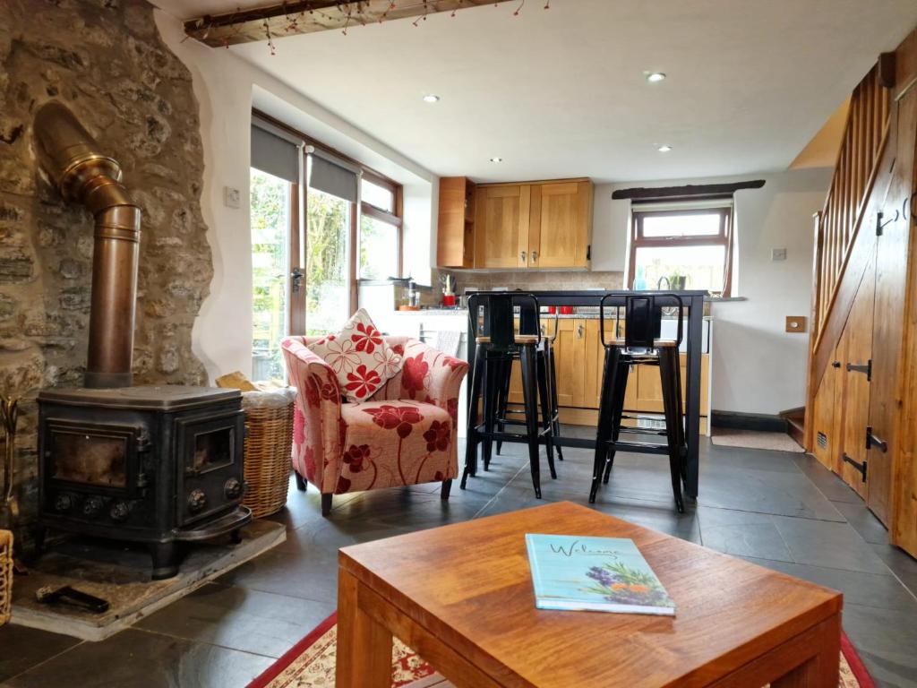a living room with a stove and a kitchen at LYDONIA BARN in Lydford