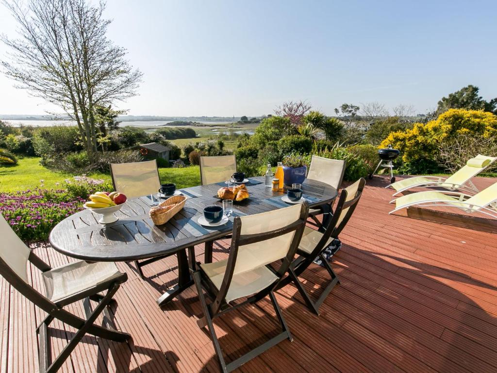 - une table à manger avec des chaises sur une terrasse en bois dans l'établissement Holiday Home Villa Panorama Mer by Interhome, à Plounéour-Trez