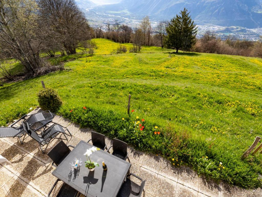 a patio with a table and chairs and a green field at Chalet Maison Le Fontany by Interhome in Randogne