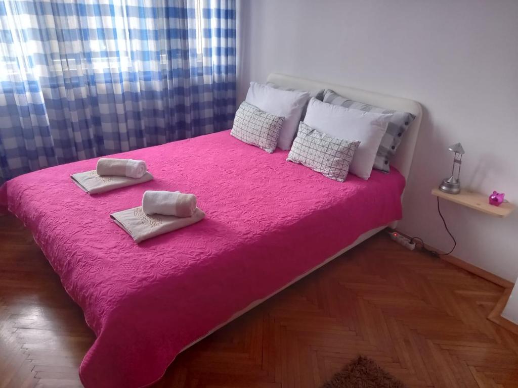 una camera da letto con un letto rosa con due asciugamani di Stan u centru a Podgorica