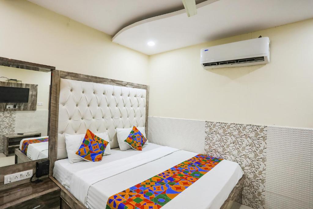 1 dormitorio con 1 cama grande y almohadas coloridas en FabHotel Welcome, en Kānpur