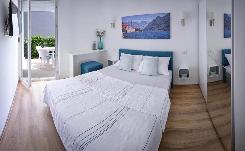 una camera da letto con un grande letto bianco con testiera blu di Solimar a Budua