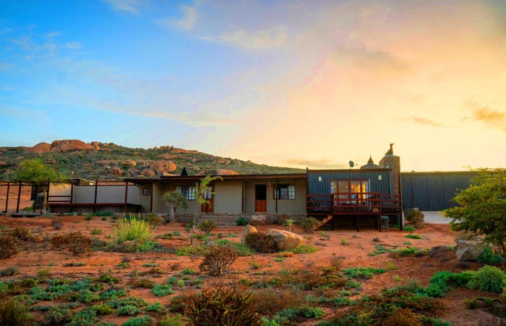 a house in the desert with a hill in the background at Nuwefonteinskop Lodge in Kotzesrus