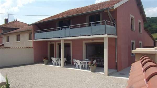 a red house with a balcony and tables and chairs at AU DOMAINE DE CHASSE in Beauvoir-de-Marc