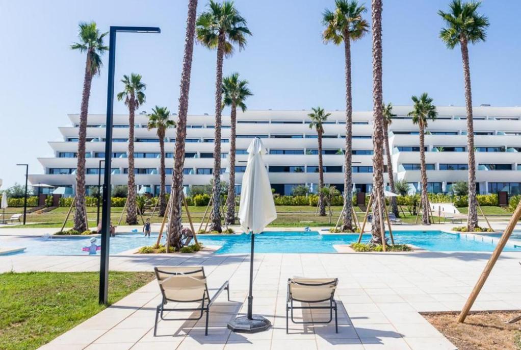 a pool with chairs and palm trees in front of a building at Luxury Duplex Penthouse Denia in Denia